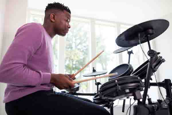 teenage boy practicing drum kit at home depicting sound dampening of foam insulation