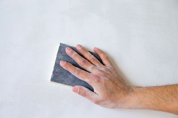 image of a painter sanding spray foam after it has cured