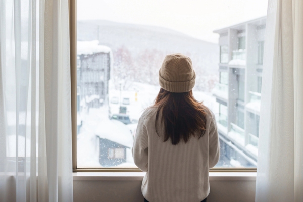 woman looking out the window depicting frost on windows during winter