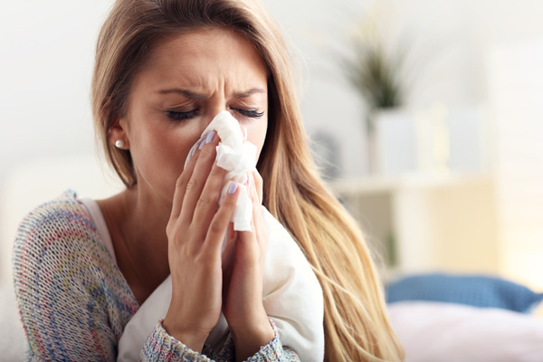 woman sneezing due to poor indoor air quality due to fiberglass insulation