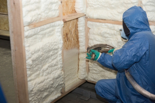 worker wearing full protective gear while applying spray foam