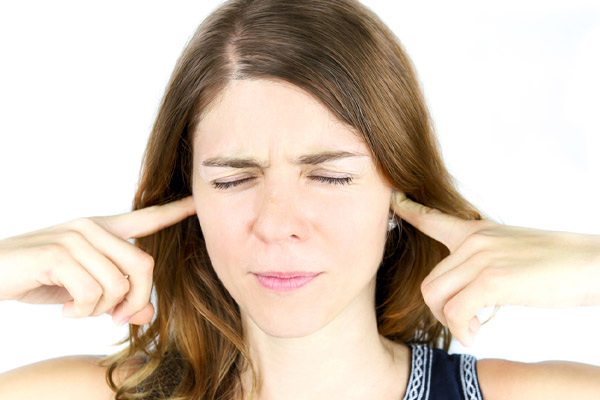 image of homeowner covering ears due to oud outdoor noise and poor insulation