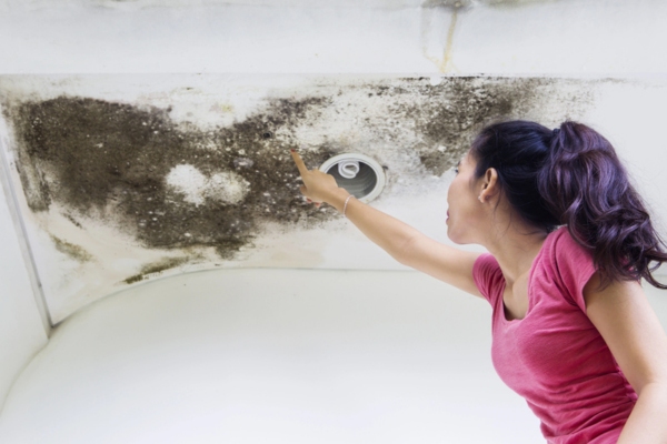 woman pointing at ceiling mold due to inadequate ventilation at home