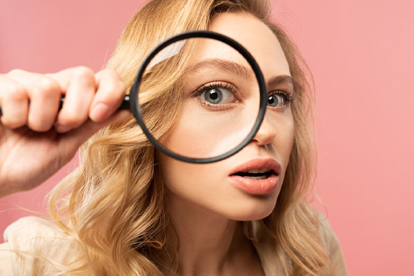 close up of a woman looking through a magnifying glass depicting top signs of poor indoor air quality
