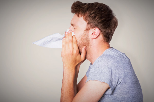 man sneezing due to poor indoor air quality and allergens