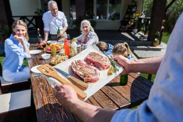 image of a homeowner grilling outside to prevent heat inside home