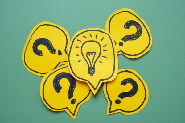 Question marks and lightbulb drawn on paper and cut in speech bubble shapes depicting Keeping Your Home Cool in Summer FAQs