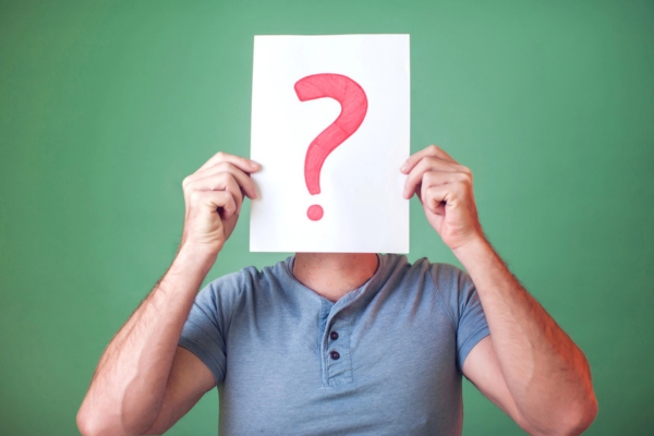 question mark on a paper held by a man in front of his face depicting FAQs about Insulation and Home Resale Value