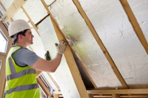 Professional worker adding building insulation during construction