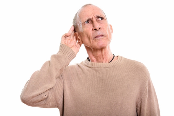 senior man cupping ear while looking up and listening to outdoor noise