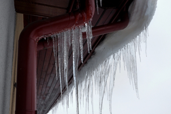 Ice dams hanging from the roof and gutters of a house