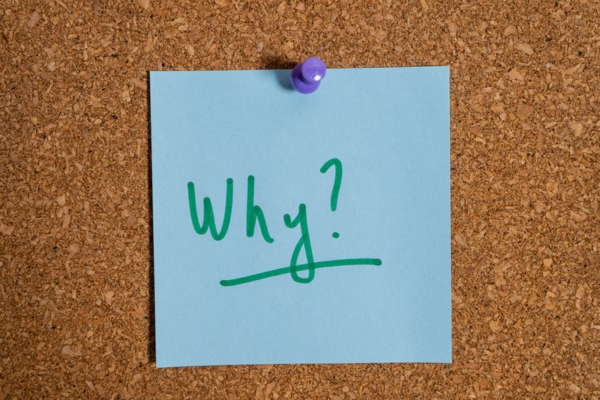 WHY handwritten on a blue sticky note