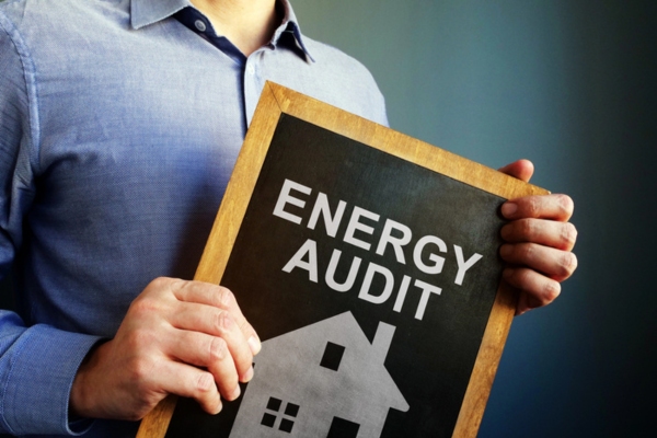 man holding a small chalkboard that says Energy Audit