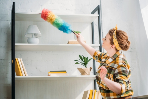 woman dusting shelves at home