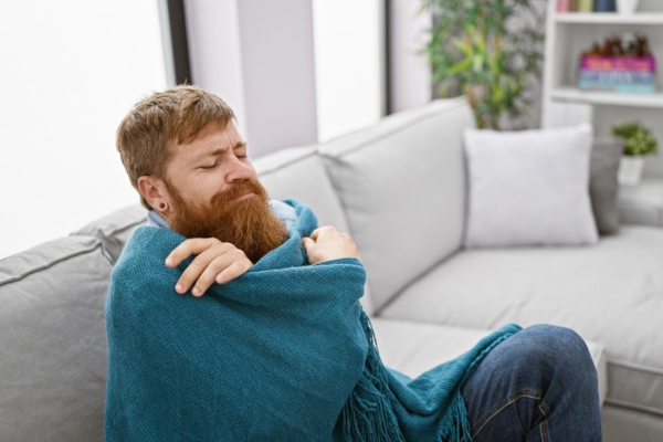 bearded man covered in blanket depicting cold spots in the house