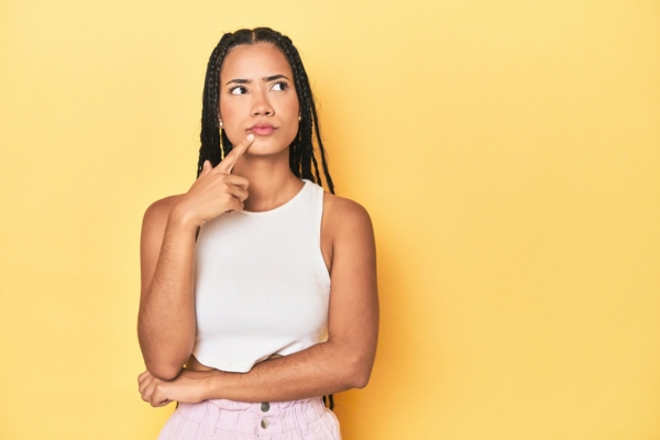 thinking woman against a yellow wall depicting Understanding Why Spring Temperatures Affect Indoor Comfort