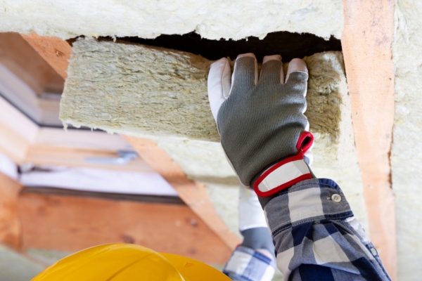 man inspecting home insulation quality to prepare for summer