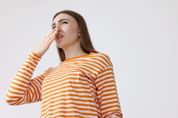 woman covering her nose due to musty smell indoors