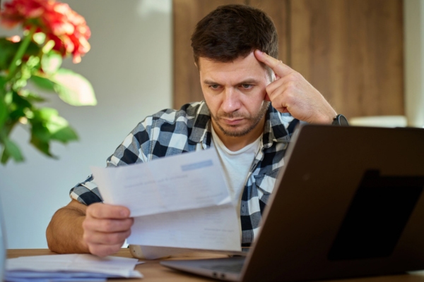 man looking at high energy bills depicting Signs Your Attic May Need More Insulation