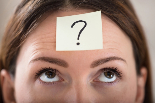 question mark on a sticky note on a woman's forehead depicting Air Conditioner Care FAQs