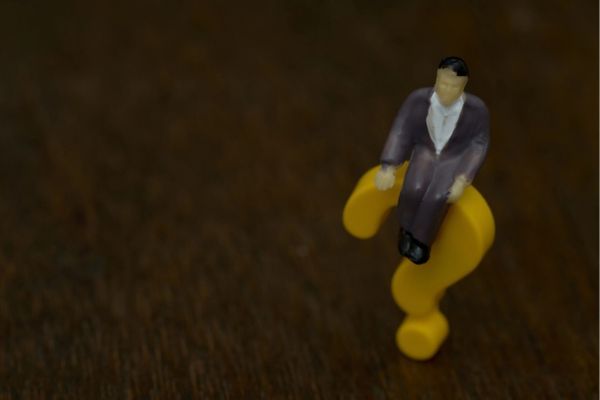 3D question mark sign with a miniature man sitting on top depicting AFUE vs AFUE2 questions