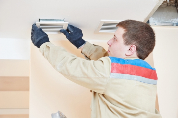 professional handyman tending to home ventilation system