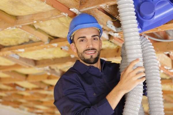 worker holding a ventilation duct in an insulated ceiling